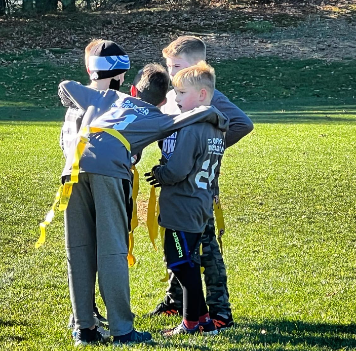 Photo of four children in a huddle during the Flag Football Turkey Bowl