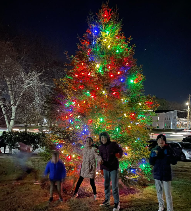Photo of children infront of lit up tree during winter